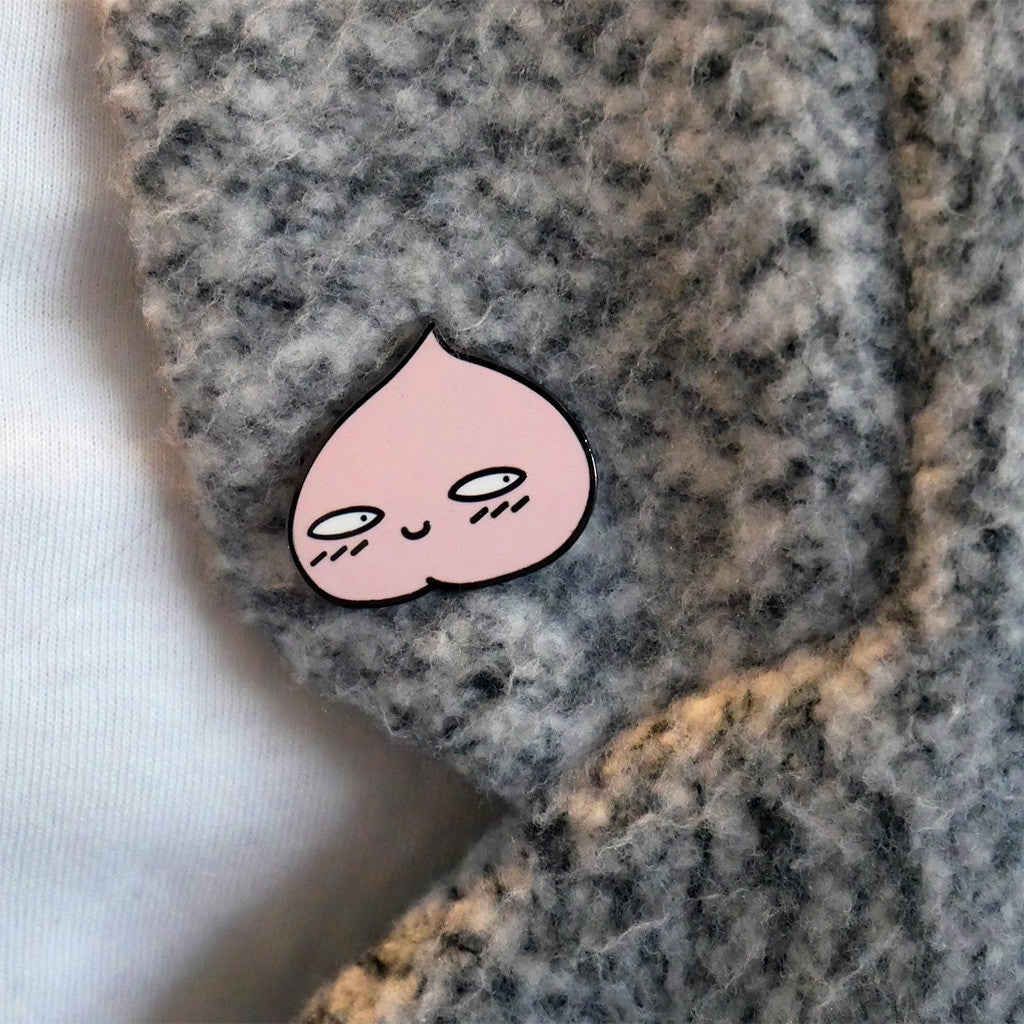 Peachy peach enamel pin posed